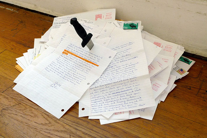 documentation photo of a pile of letters with a knife stabbed into it