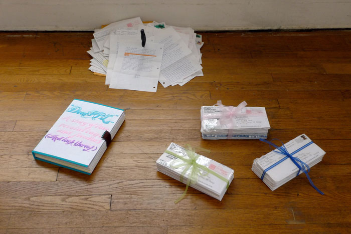 documentation photo of a handmade book, a pile of letters with a knife stabbed into it, and three bundles of letters tied with ribbon