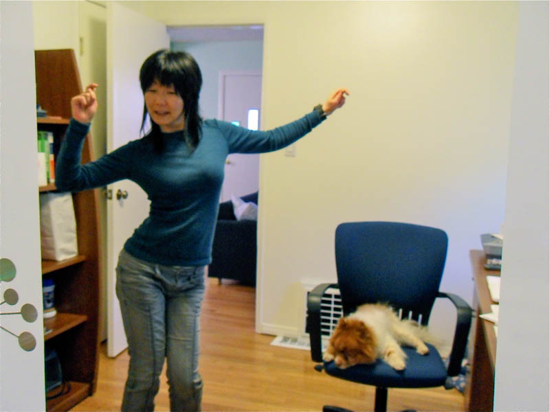 photo of Jennifer Moon dancing in her office while Mr. Snuggles sleeps on her chair